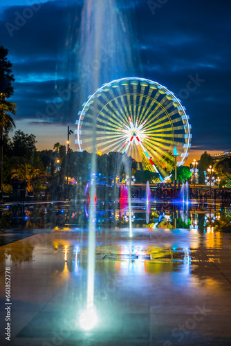 Water Fountain and Ferris Wheel in Dusk in Nice in Provence-Alpes-Côte d'Azur, France.