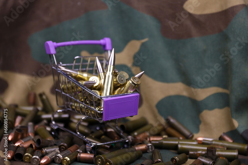Rifle cartridges in small shopping cart. Big caliber ammo cartridges with a small shopping basket