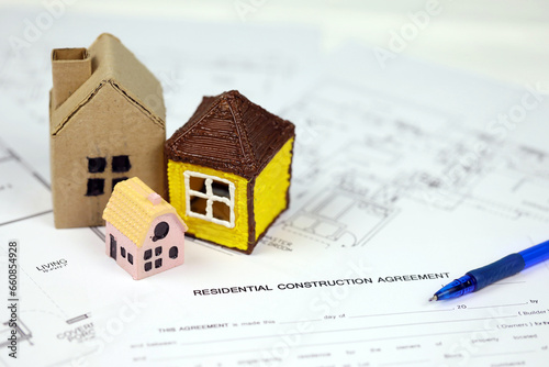 Residential construction agreement ready to sign with small toy houses and pen. Construction contract