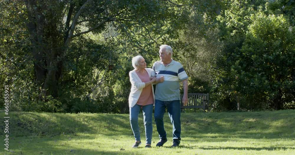 Happy senior caucasian couple walking in sunny garden, slow motion Happy senior caucasian couple walking in sunny garden, slow motion