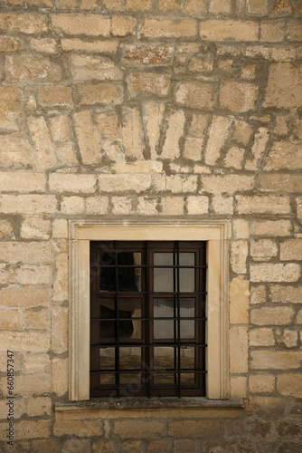 Fototapeta Naklejka Na Ścianę i Meble -  Very old window in brick stone wall of castle or fortress of 18th century. Full frame wall with window