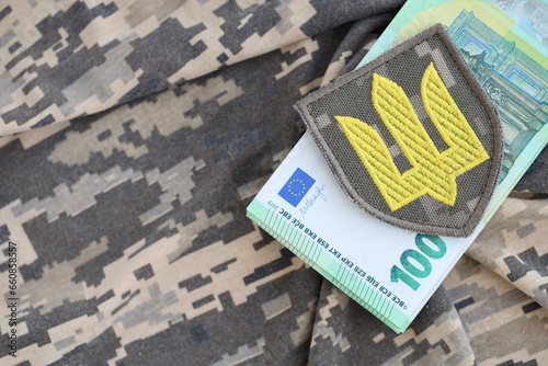 Ukrainian army symbol and bunch of euro bills on military uniform. Payments to soldiers of the Ukrainian army from European union, salaries to the military. War support photo