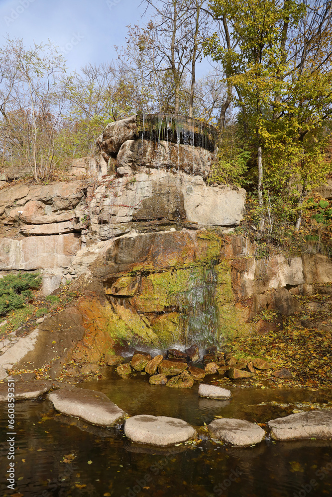 Beautiful waterfall between large rocks in autumn forest. Sofievskiy park in Uman, Ukraine