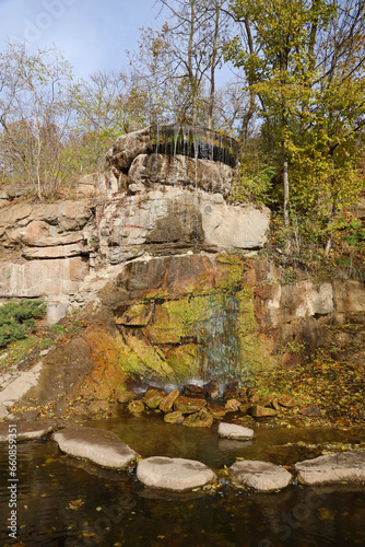 Beautiful waterfall between large rocks in autumn forest. Sofievskiy park in Uman, Ukraine
