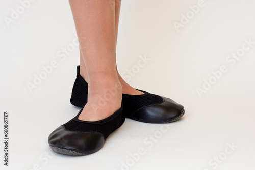 Cropped child legs in black leather ballet shoes