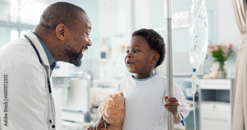 Pediatrician, happy and doctor playing with child as care, support and kindness in healthcare in a hospital or clinic. Iv drip, teddy bear and African professional with medical compassion for kid