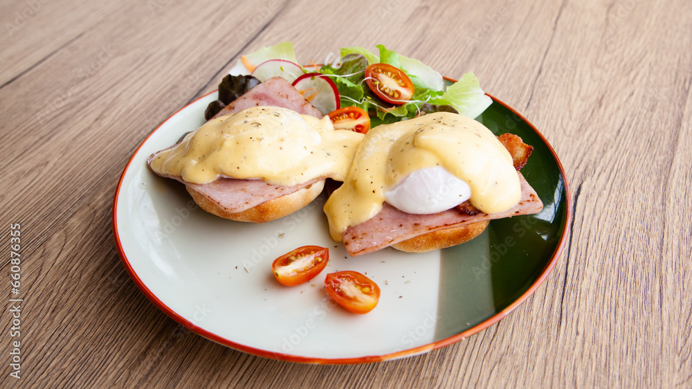 Eggs Benedict, breakfast and brunch, made from poached egg, English muffin, ham, bacon, Hollandaise sauce and mixed salad Eggs Benedict, breakfast and brunch, made from poached egg, English muffin, ham, bacon, Hollandaise sauce and mixed salad