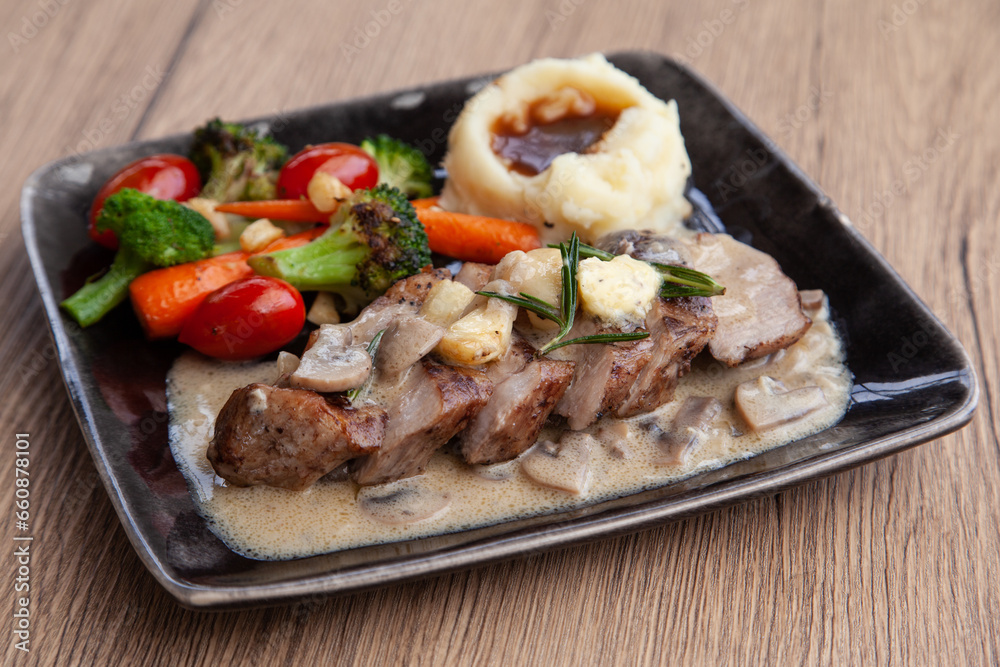 Pork shoulder steak with mushroom sauce, mashed potatoes and grilled vegetable