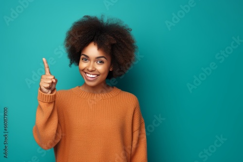 happy woman showing index finger on blue background. generative ai. photo