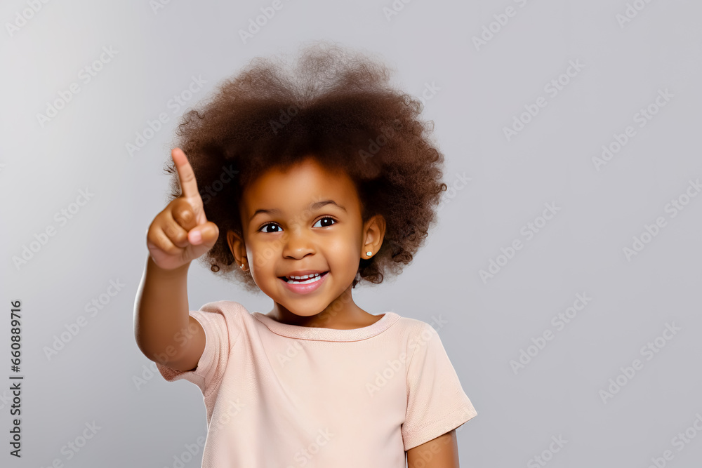 Happy little African American girl pointing finger up. Happy little African American girl pointing finger up.