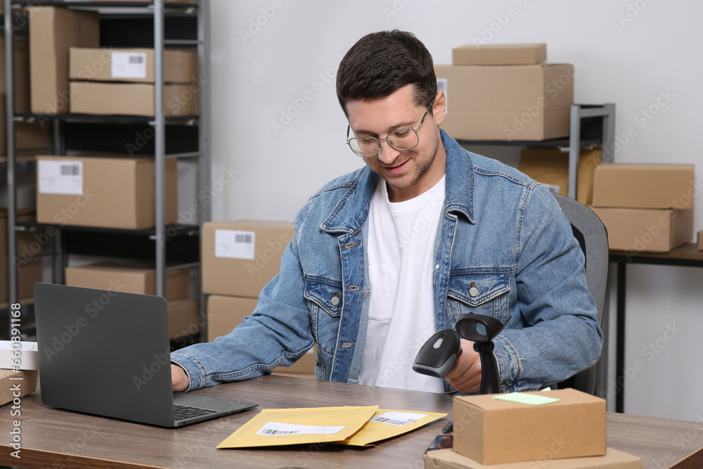 Seller with scanner, parcels and laptop at table in office. Online store Seller with scanner, parcels and laptop at table in office. Online store