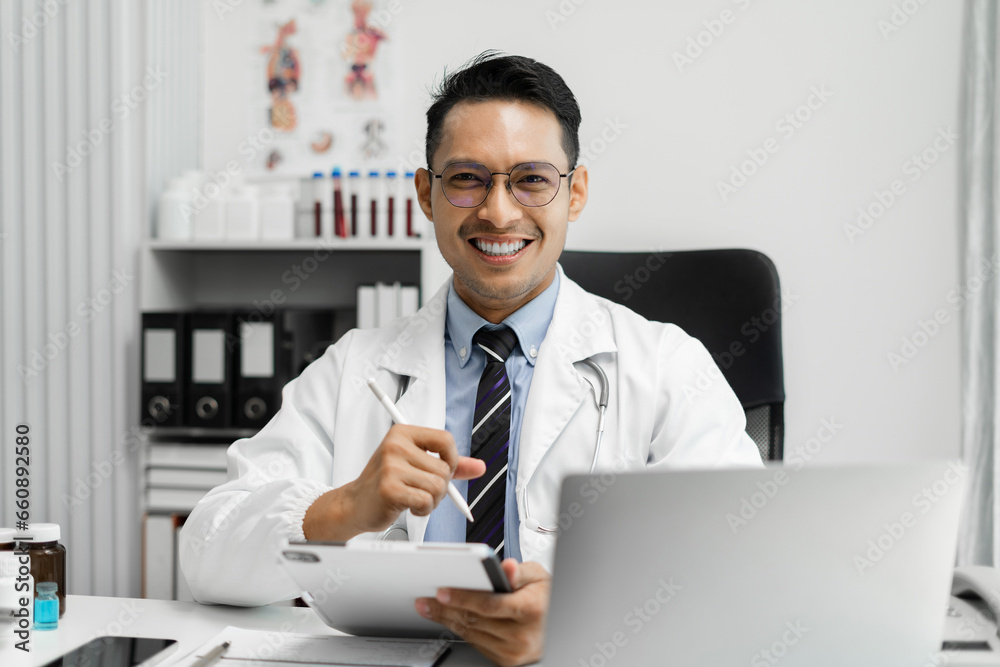 male doctor sitting at a desk, looking at the camera. male doctor sitting at a desk, looking at the camera.