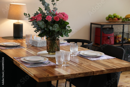 Beautiful table setting with bouquet indoors. Roses and eucalyptus branches in vase