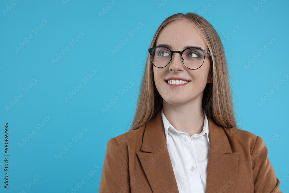 Portrait of happy young secretary on light blue background, space for text