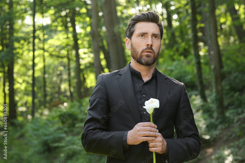 Sad man with calla lily flower outdoors. Funeral ceremony