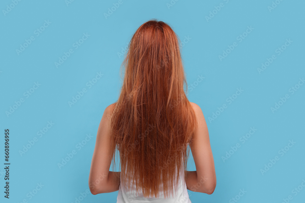 Naklejka premium Woman with damaged messy hair on light blue background, back view