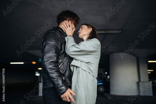 young couple in love hugging on a date in a leather jacket and raincoat in an underground parking lot. Relationship concept