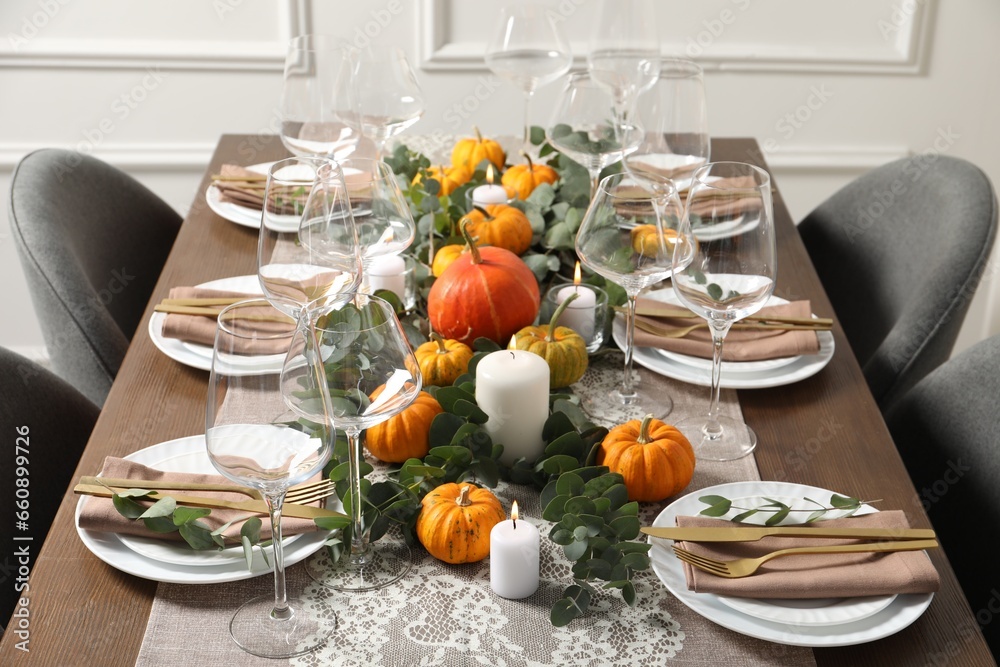 Fototapeta premium Beautiful autumn table setting. Plates, cutlery, glasses, pumpkins and floral decor