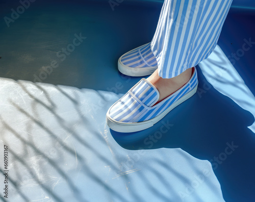 a person's feet wearing slip on shoes with blue stripes