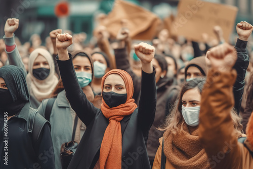 Muslim woman wearing protective face mask and supporting anti-racism movement with group of people on city streets. © FutureStock