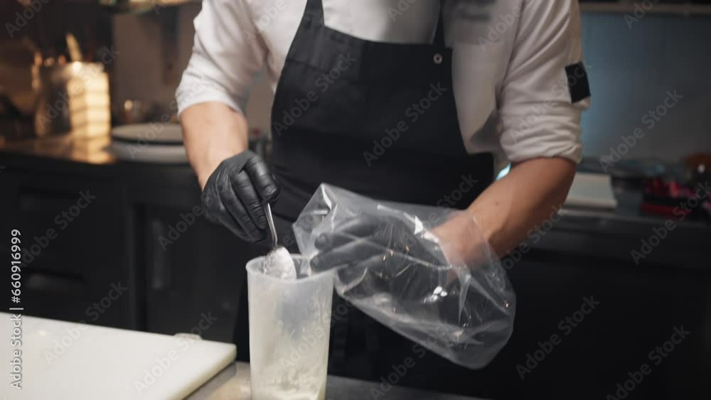 Chef puts sauce in sac a poche into restaurant kitchen