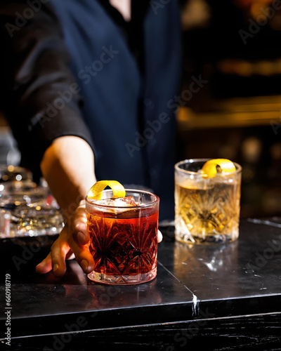 Red cocktail poured from shaker into glass on napkin on bar