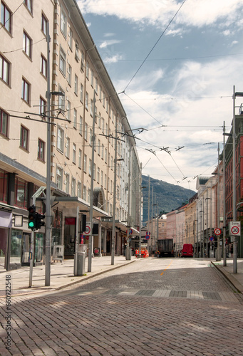 Empty street during the day with bright buildings around and a visible hill, pedestrian crossing