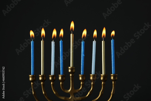 Hanukkiah with burning candles on black background
