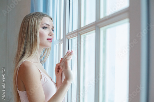 Cheerful young model woman with blonde hair and makeup looking at window indoor portrait Free Download Cheerful young model woman with blonde hair and makeup looking at window indoor portrait - GFXLoad