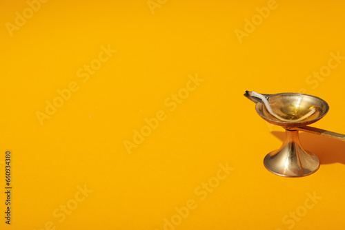 Copper lamp with oil and wick on orange background, space for text