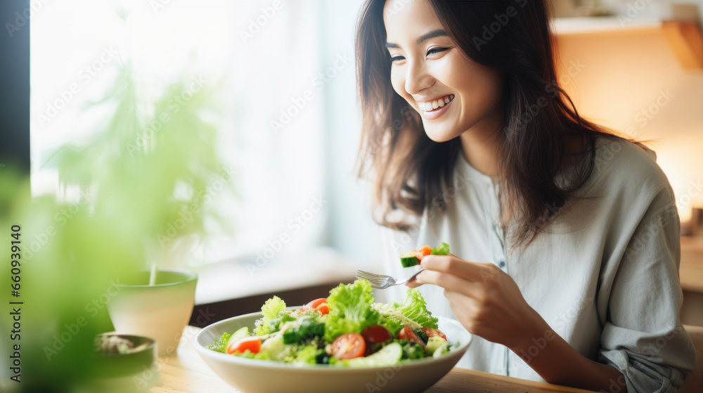 Young athletic woman eats a salad in her plate while eating breakfast