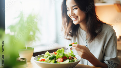 Young athletic woman eats a salad in her plate while eating breakfast