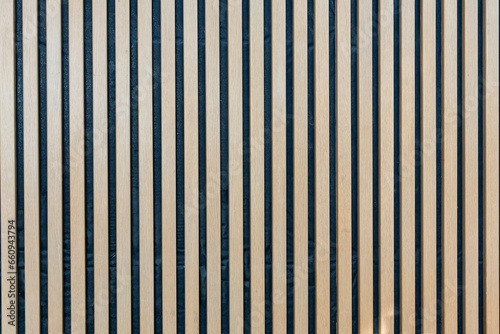 A three dimensional vertical seamless pattern of modern wall paneling with vertical wooden slats for a wall. A light brown wooden slats texture for interior decoration.