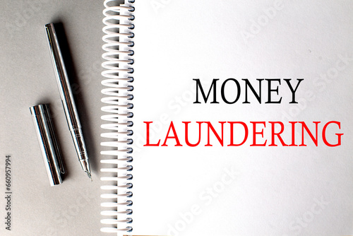 MONEY LAUNDERING text on a notebook with pen on grey background