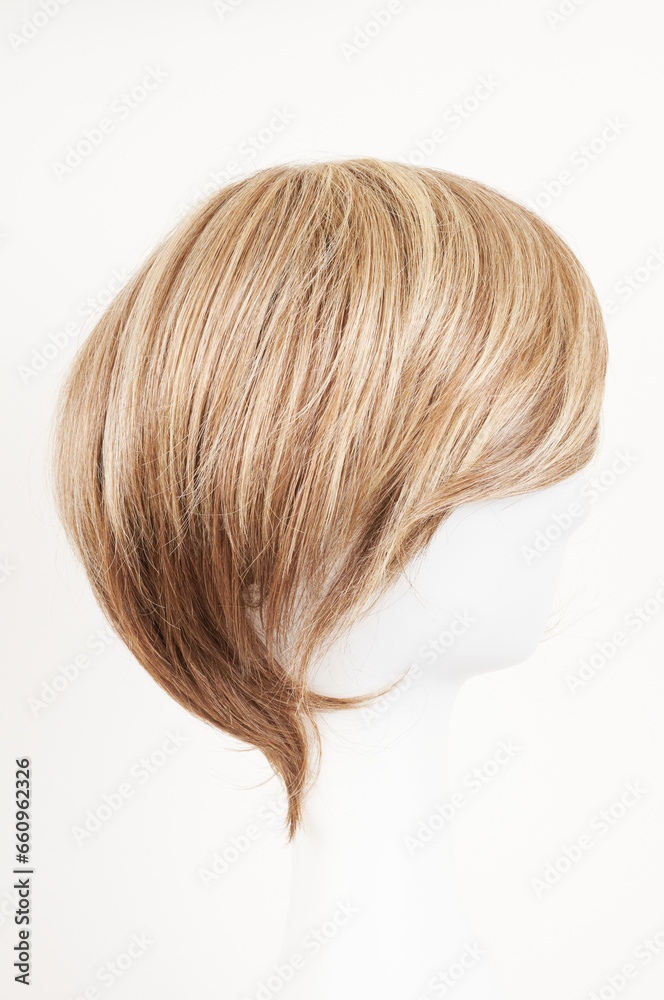 Natural looking blonde fair wig on white mannequin head. Short hair cut on the plastic wig holder isolated on white background, side view.