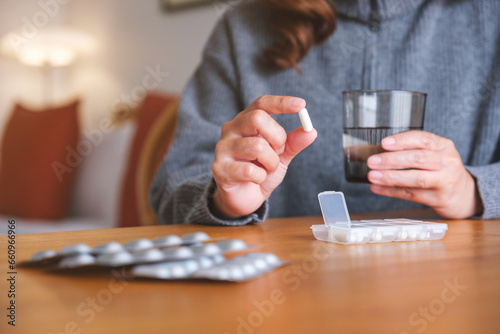 Closeup image of a woman holding pills and a glass of water