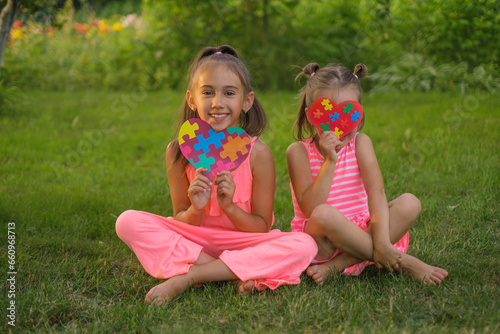 Girls with puzzle cards show their love and support to children suffering from autism syndrome.