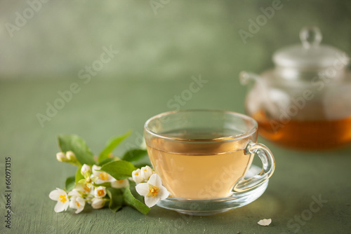 Composition with cup of jasmine  tea and flowers on green background photo