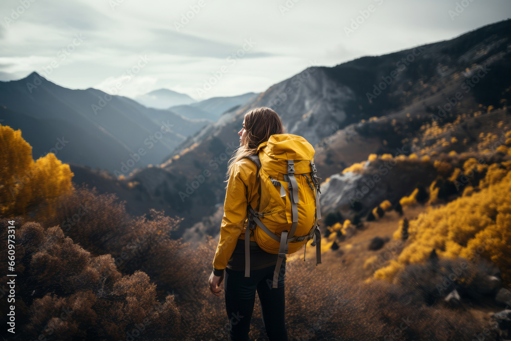 A beautiful girl in a yellow jacket with a backpack walks in the mountains. A girl in a yellow jacket travels in the mountains. travel concept