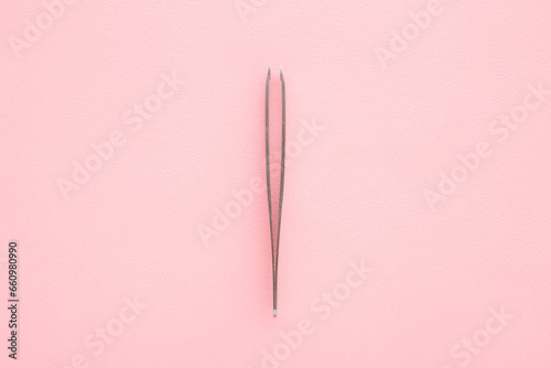 New tweezers on light pink table background. Pastel color. Closeup. Top down view. © fotoduets