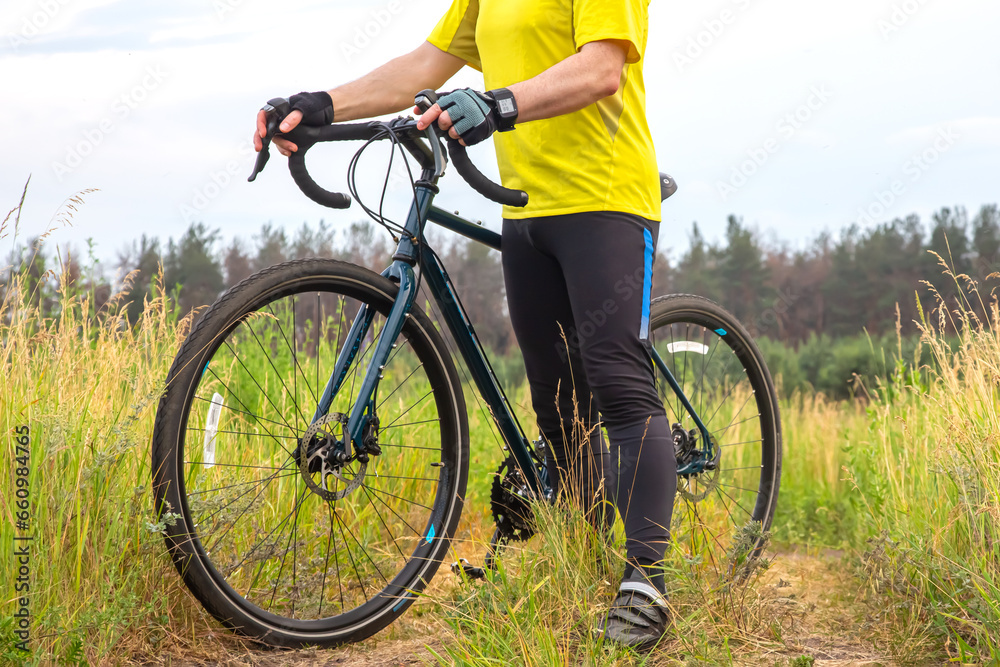 Fototapeta premium man cyclist in yellow clothes is resting on a bicycle on the road in nature. sports, hobbies and entertainment for health