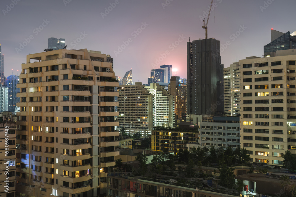 View of high-rise buildings at night in Bangkok. Housing and living in a high-density district. View of high-rise buildings at night in Bangkok. Housing and living in a high-density district.