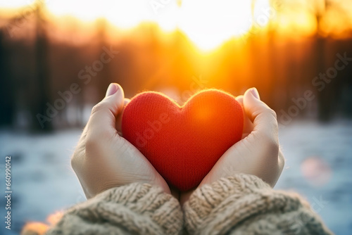 Close up of woman holding heart symbol shaped in background of winter view. Lifestyle concept of drinks and rest. photo