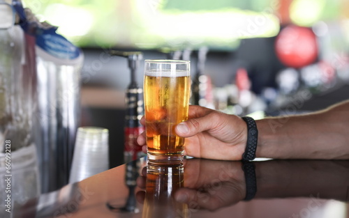Man s hand holds glass of beer on bar. All inclusive in hotels in concept resorts
