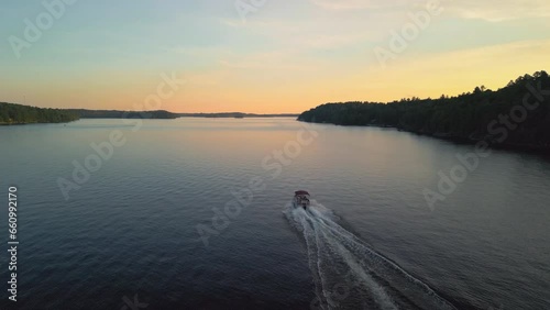 An aerial of a pontoon boat cruising on a lake at sunset photo