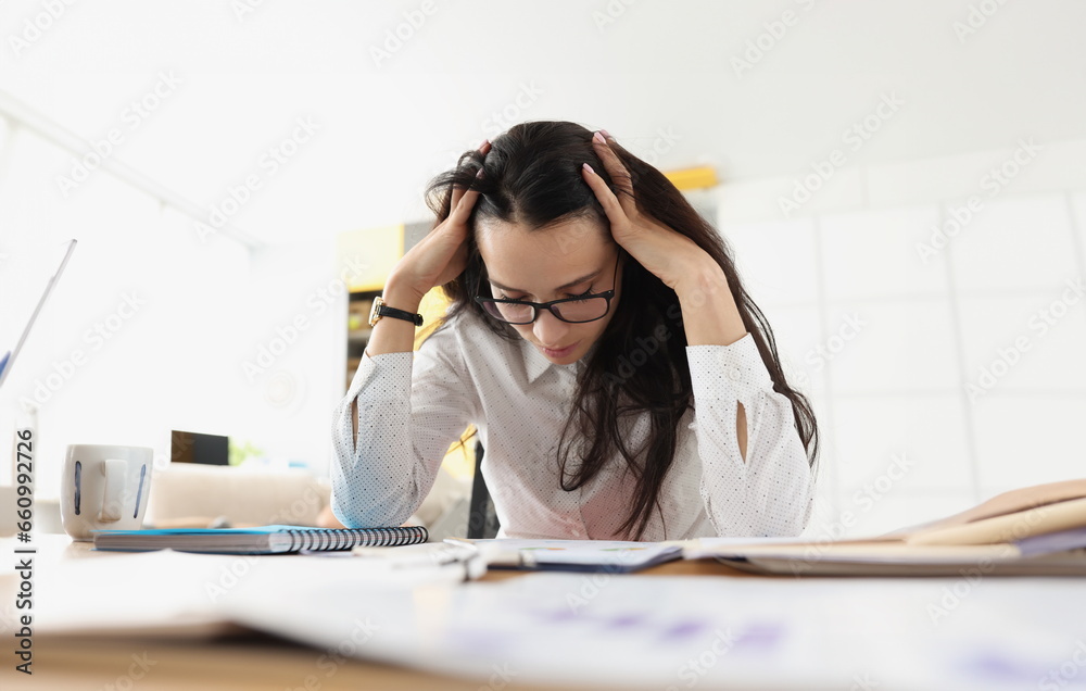 Tired woman bowed her head over her desk with documents. Stressful situations at work concept Tired woman bowed her head over her desk with documents. Stressful situations at work concept