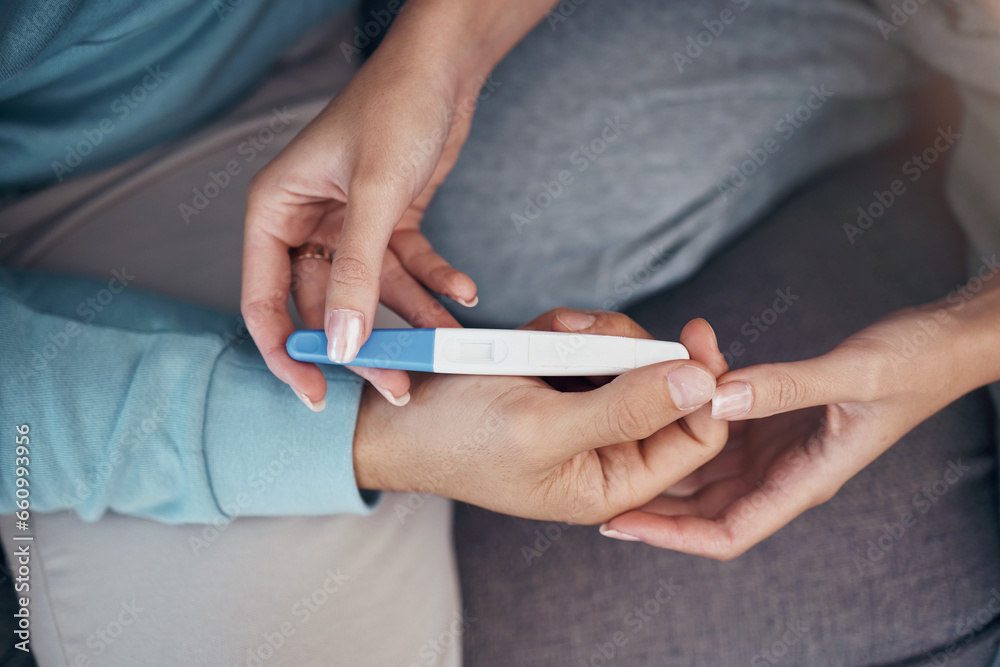 Couple, hands and holding of pregnancy test in closeup for family planning, future and love on sofa in space. Man, woman and married with result on stick for news of fertility with support for care