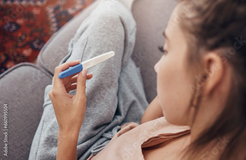 Pregnancy test, waiting and woman on sofa in home, reading news and check results.,Stick, sad and pregnant mother in living room for future maternity, ivf fertility and anxiety, depressed or serious photo