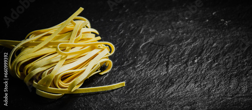 Homemade pasta tagliatelle. On black table.