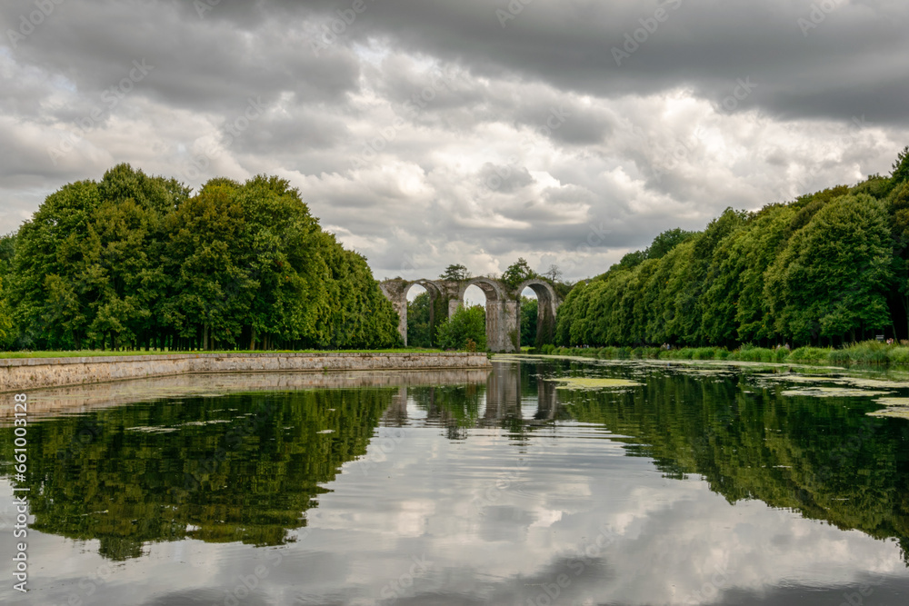 Green summer landscape with a river and trees and an aqueduct